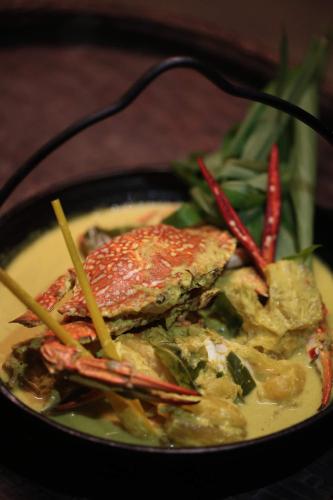een zwarte kom voedsel met vlees en groenten bij Kunang Kunang Heritage Villas in Pantai Cenang