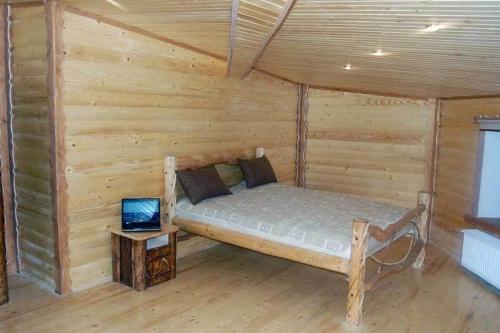 a bed in a log cabin with a laptop on a table at Panorama Karpat in Yablunytsya