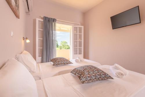 2 białe łóżka w pokoju z oknem w obiekcie Relax Studios Corfu w Rodzie