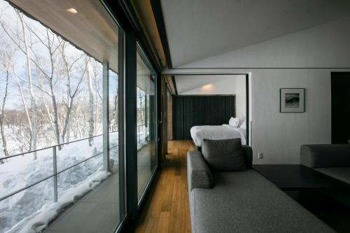 a room with a couch and a bed and a window at Zaborin in Niseko