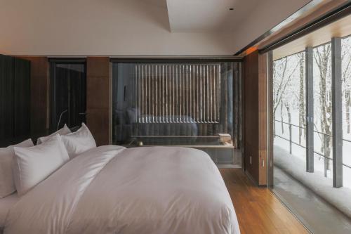 a bedroom with a large white bed and large windows at Zaborin in Kutchan