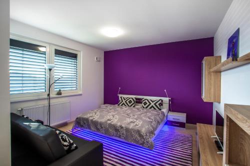 a purple bedroom with a bed and a couch at Air-Conditioned City View Apartment 24h check-in in Bratislava