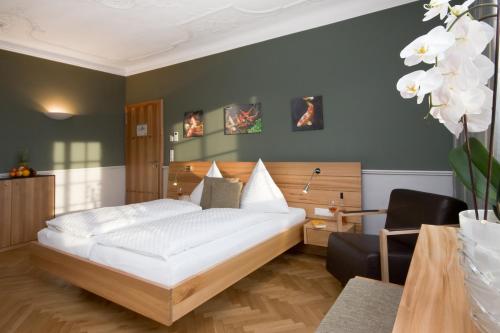 een slaapkamer met een groot wit bed en een stoel bij Hotel Der Löwen in Hagnau