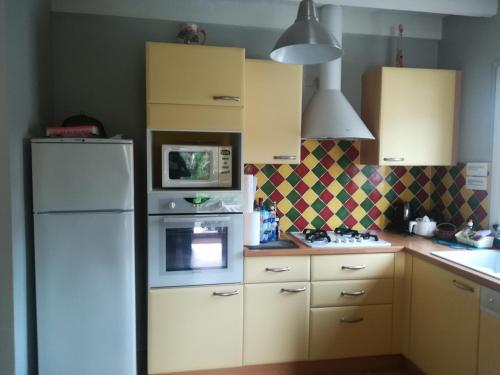 La cuisine est équipée d'un réfrigérateur blanc et d'un four micro-ondes. dans l'établissement Maison Valras accès direct à la plage, à Valras-Plage