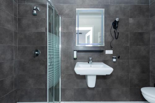 y baño con lavabo y ducha con espejo. en Villa Solaris, en Pobierowo