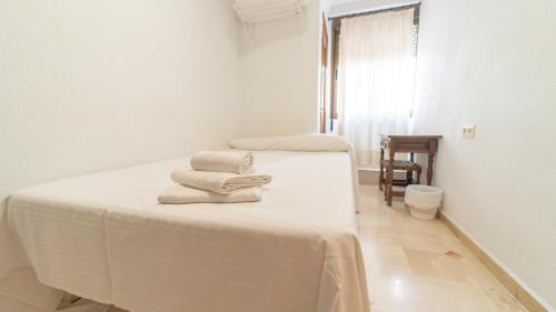 two beds in a white room with towels on them at Hostal Bocanegra in Granada