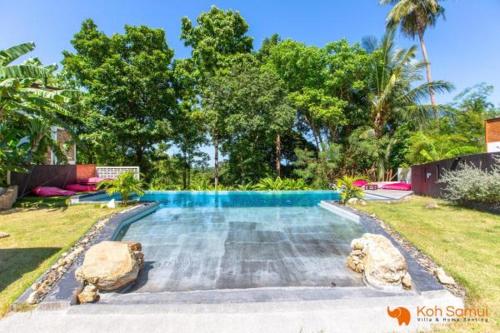ein Schwimmbad mit zwei großen Felsen im Hof in der Unterkunft Sabri in Chaweng