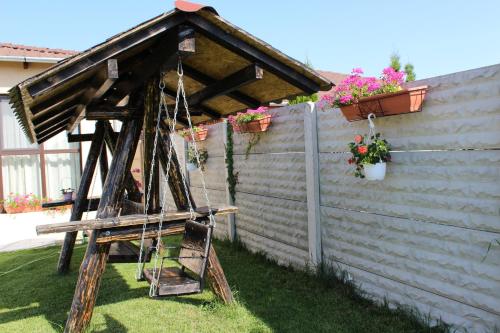 a wooden swing in a yard next to a fence at Sia & Sophie House Oradea in Sîntandrei
