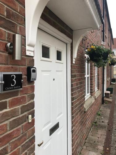 a white door on the side of a brick building at 3 Crown Barton, Glastonbury in Glastonbury