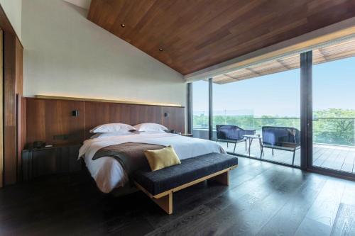 Un dormitorio con una cama grande y un balcón. en MUH SHOOU XIXI HOTEL HANGZHOU, en Yuhang