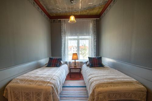 two beds in a room with a window at Boutique Hotel Langin Kauppahuone in Raahe