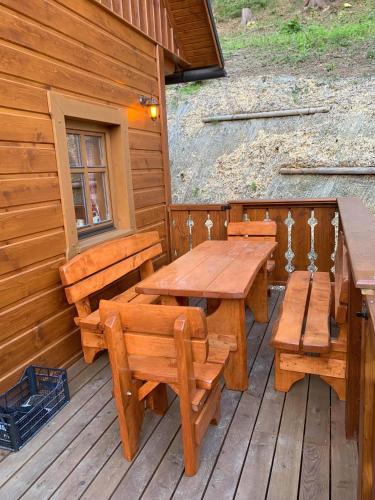 a wooden deck with tables and benches on a cabin at Chalupa na Leskové in Velké Karlovice
