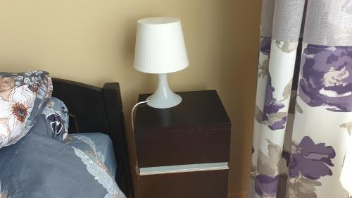 a lamp on a night stand next to a bed at Camino Cesis in Cēsis