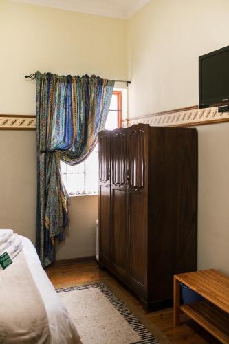a bedroom with a brown refrigerator and a window at Van Dykshuis Guest House in Heidelberg