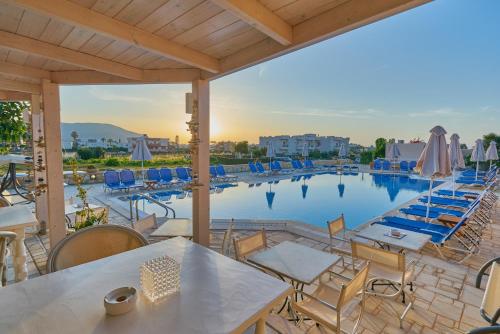 een uitzicht op het zwembad in een resort met tafels en stoelen bij Golden Bay Hotel Apartments in Malia