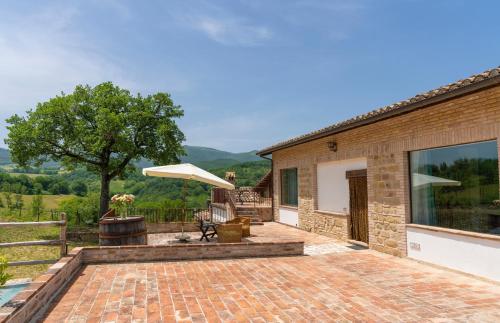 a brick patio with a table and an umbrella at Azzurro di Vallepietra in Camporotondo di Fiastrone