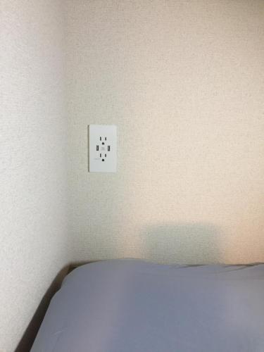 a white switch on a wall next to a bed at Heart Hostel and Diner 女性専用Onlyfemale in Ise