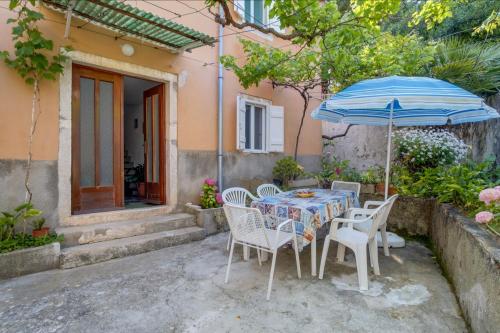 a table and chairs with an umbrella in front of a house at Apartments Ivna in Veli Lošinj