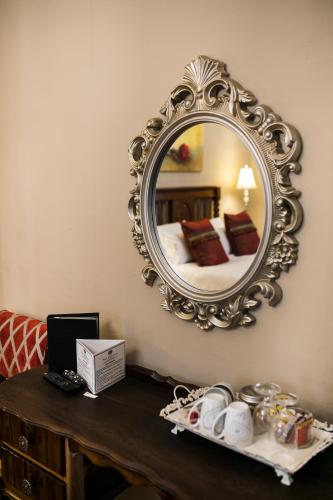 a mirror on a wall above a table with a bed at Van Dykshuis Guest House in Heidelberg
