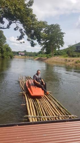 a man sitting in a row boat on a river at Kaengkrachan River Hut in Kaeng Krachan