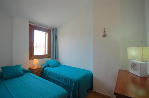 a bedroom with two blue beds and a window at Lets Holidays Heart of Tossa Apartment in Tossa de Mar