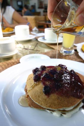 uma pessoa despejando calda sobre uma pilha de panquecas em um prato em 357 Boracay Resort em Boracay
