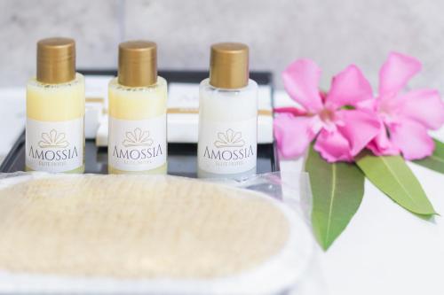 three bottles of cosmetics sitting on a table with pink flowers at AMOSSİA Elite Boutique Hotel in Turunc