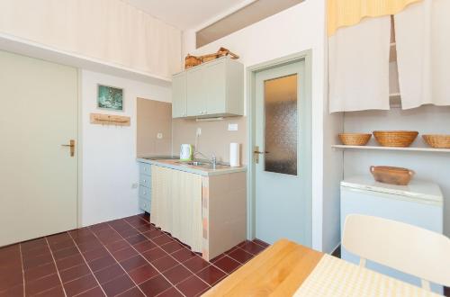 a small kitchen with white cabinets and a table at Apartman ORLOVAC in Slime