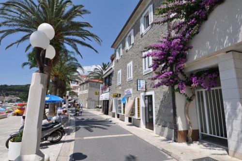 a street with a palm tree and a building with purple flowers at Villa DELFINA in Podgora