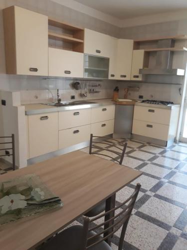 a kitchen with white cabinets and a wooden table at Hotel Terme Villa Teresa in Ischia