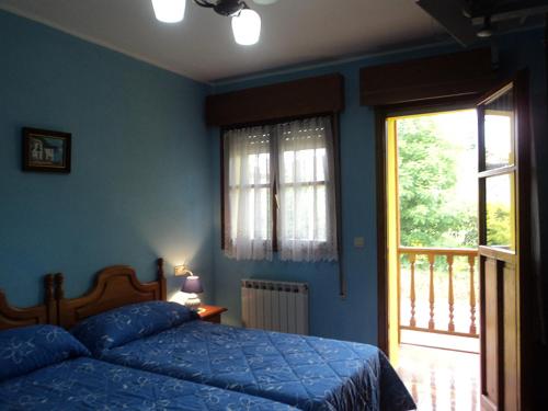 a blue bedroom with a bed and a window at APARTAMENTOS RURALES PERNÚS in Colunga