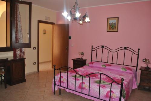 a bedroom with a bed with pink sheets and a chandelier at Ippocampo B&B in Licata