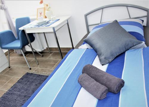 a bed with blue and white sheets and a desk and a chair at ZV-Scholtz Gästehaus Neuötting Simbacher Straße 7 in Neuötting