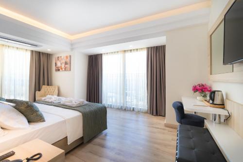 a hotel room with a bed and a desk and window at AMOSSİA Elite Boutique Hotel in Turunc
