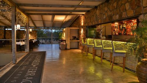 a restaurant with a bar with chairs and a table at Bushveld Terrace Safari Hotel, Lodge & Spa in Phalaborwa