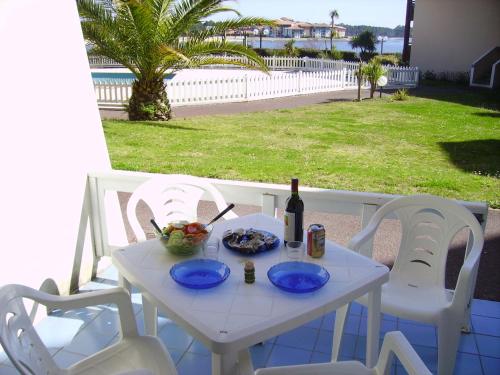 - une table et des chaises blanches avec une bouteille de vin dans l'établissement Les Landes avec piscine et près du lac, à Vieux-Boucau-les-Bains