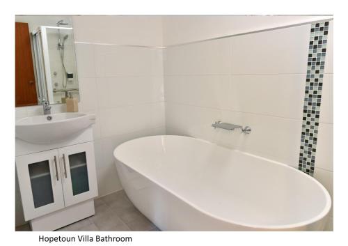 un bagno bianco con vasca e lavandino di Hopetoun Villa a Woonona