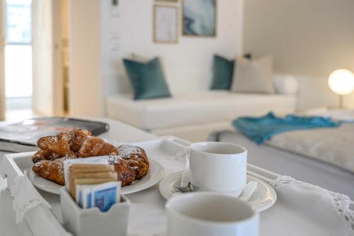 een tafel met een dienblad met gebak en kopjes koffie bij Hotel Astoria in Bibione