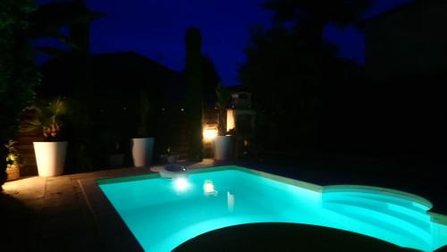 a swimming pool lit up at night at Le patio d'olivier in Lalinde