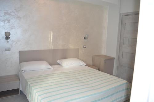 a white bedroom with a bed with two pillows at Sotto il Cielo del Cilento in Ostigliano
