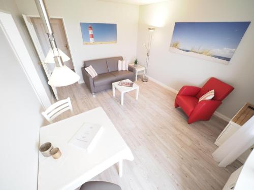 uma sala de estar com um sofá e uma cadeira vermelha em Appartement-67 em Westerland