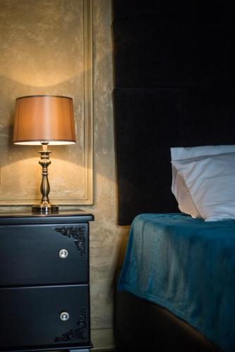 a lamp on top of a dresser next to a bed at Julina Boutique Living in Mosta