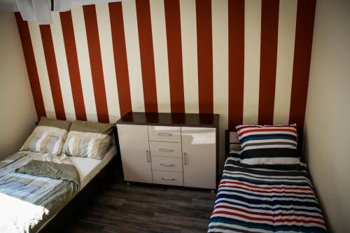 a bedroom with a bed and a dresser with a striped wall at Apartament 250m od morza! in Ustka