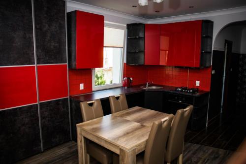 a kitchen with a wooden table and red cabinets at Apartament 250m od morza! in Ustka