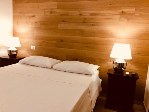 a bedroom with a wooden wall with a bed and two lamps at Conchiglia 25 in Cupra Marittima