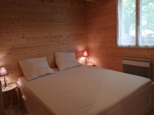 - un lit blanc dans une chambre en bois avec deux lampes dans l'établissement La Cabane - Bassin d'Arcachon - Gujan-Mestras, à Gujan-Mestras