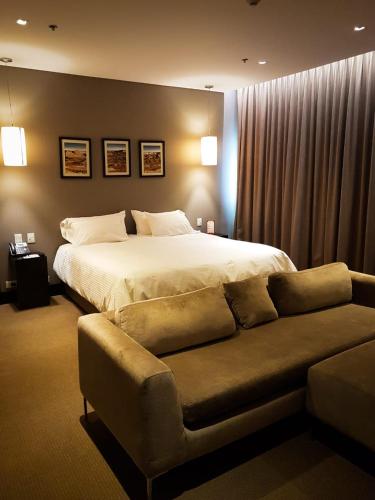 a bedroom with a bed and a couch at Hotel y Casino Del Río - General Roca in General Roca