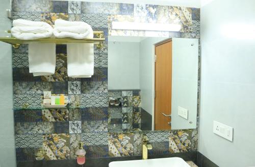 ein Badezimmer mit einem Waschbecken, einem Spiegel und Handtüchern in der Unterkunft Lalys Residency in Thrissur