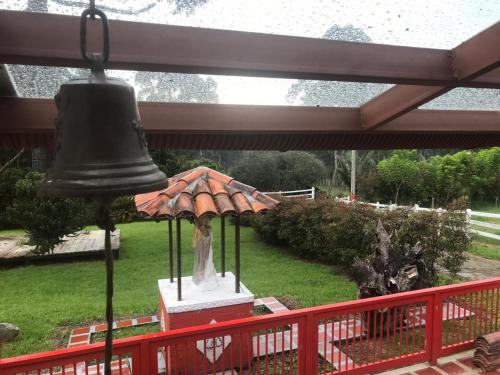 a bell on a porch with a statue under it at Ecohotel Pinohermoso Reserva Natural in Salento
