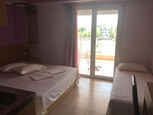 a bedroom with two beds and a door to a balcony at Dimis Studios and Apartments in Olympic Beach